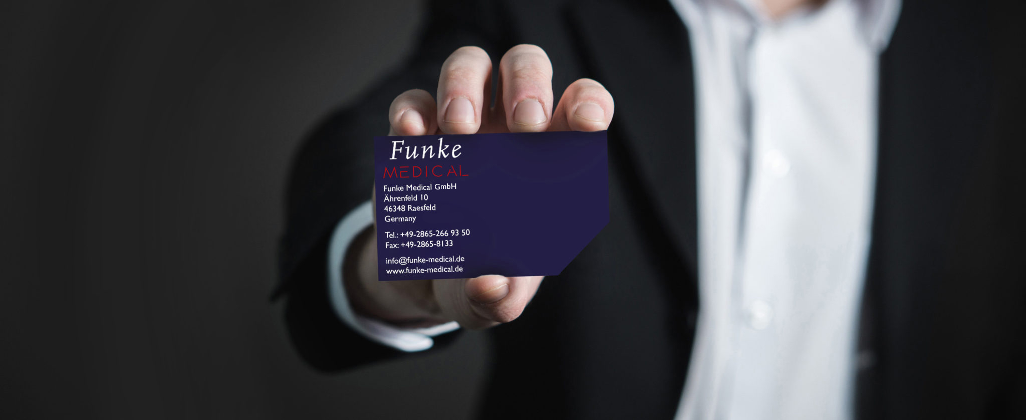 Man in suit holds a Funke Medical business card into the camera